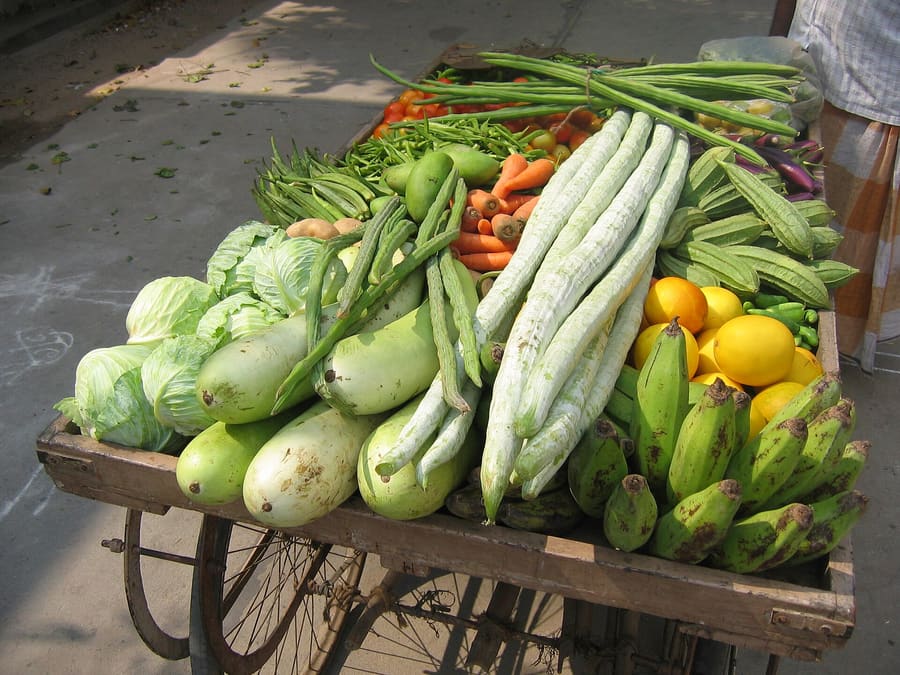 A wooden handcart loaded with gourds, cabbages, carrots and plantains